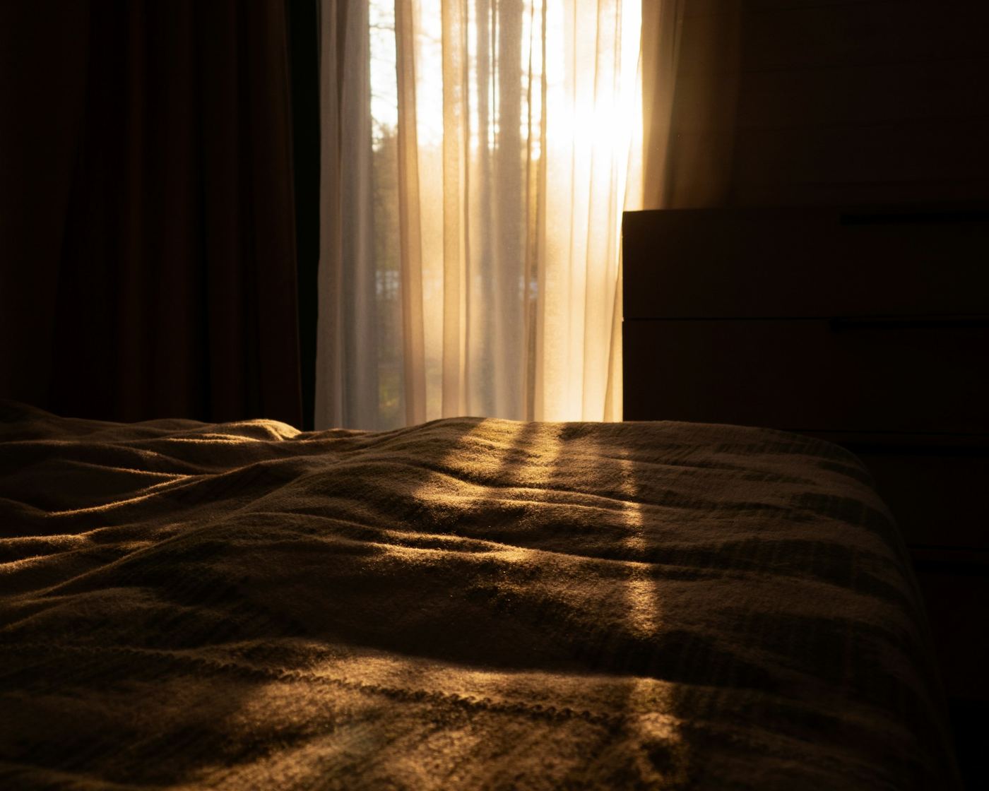 Morning sunlight through sheer curtains onto a bed