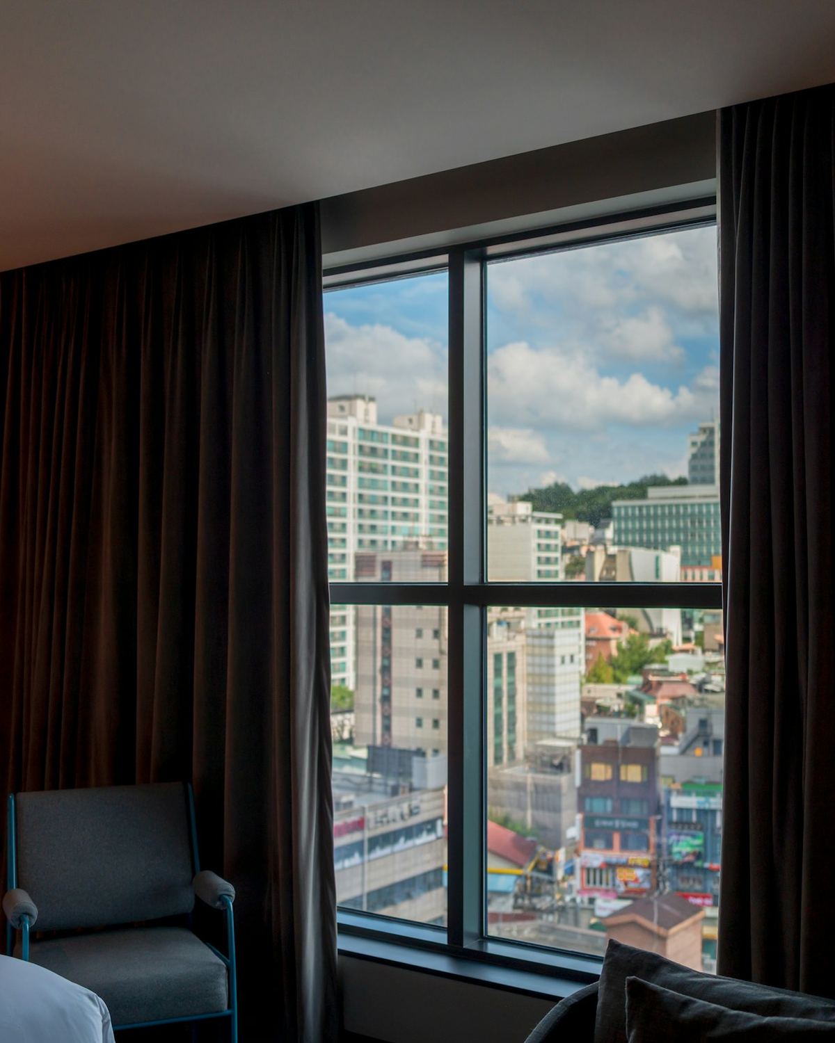 Hotel suite with a warm lamp and a city view through tall windows